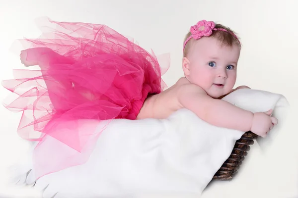 Klein meisje in een mand op een witte achtergrond — Stockfoto