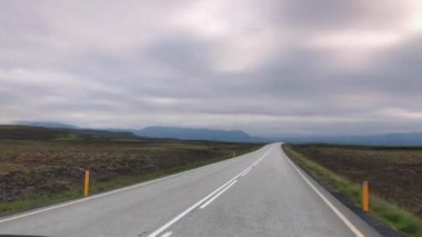 İzlanda 'da araba sürüyor. Aracın içinden yola bir göz atın. İzlanda 'nın güzel doğası, geniş alanlar, dağlar, boş uzun yollar..