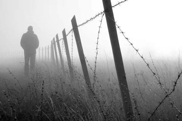 Άνθρωπος που βάδιζε κοντά σε περίπτωση πυκνής ομίχλης μηχανή αγκαθώματα φράχτη — Φωτογραφία Αρχείου