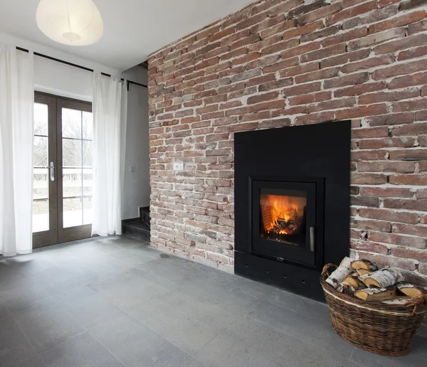 Fireplace in a brick wall and woods in basket — Stock Photo, Image