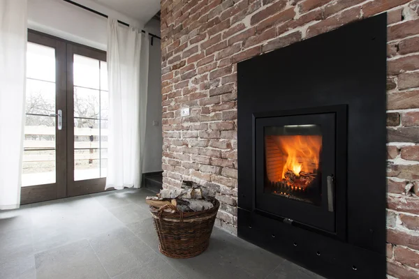 Chimenea en una pared de ladrillo y maderas en cesta — Foto de Stock