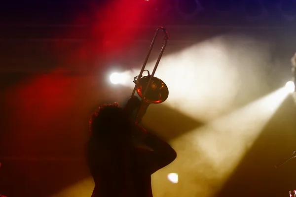 Силуэт тромбониста на сцене и абстрактный свет — стоковое фото