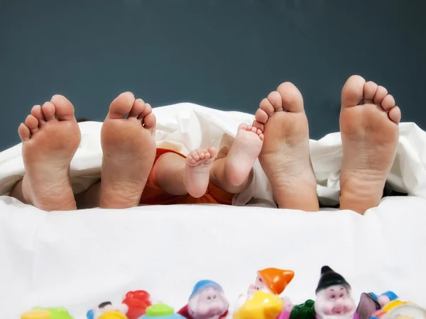 Stromový pár nohou šťastné rodiny v posteli - otec, matka a dítě — Stock fotografie