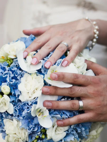 Mãos e anéis no buquê de casamento — Fotografia de Stock