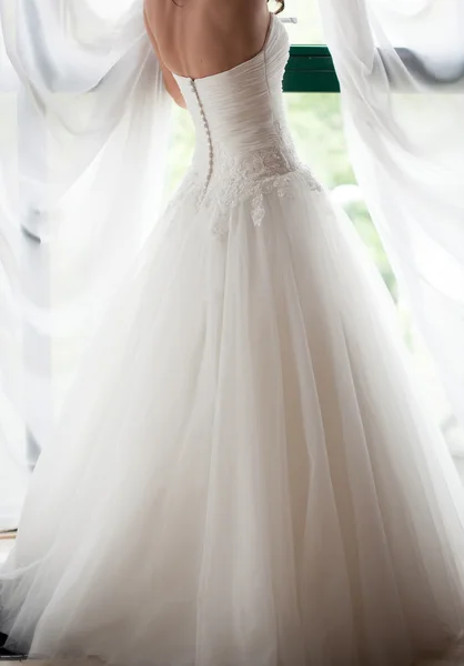 Bride in white wedding dress looking in window — Stock Photo, Image