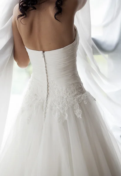 Bride in white wedding dress looking in window — Stock Photo, Image