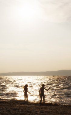 iki gün batımında sahilde oynarken siluetleri çocuk