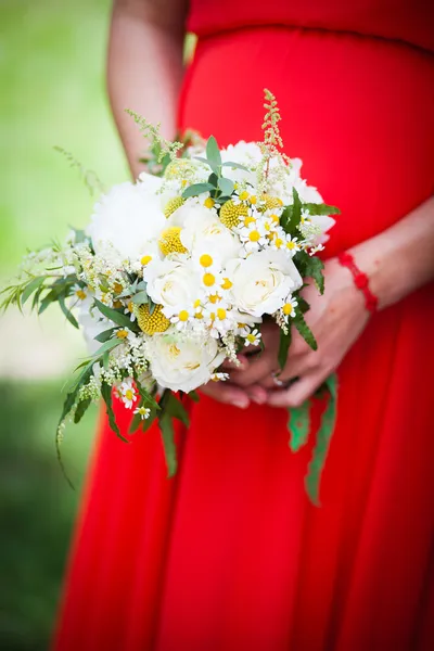 Schwangere Braut im roten Kleid mit Blumenstrauß — Stockfoto