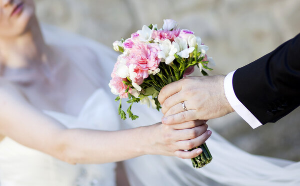 Hands and rings on wedding bouquet