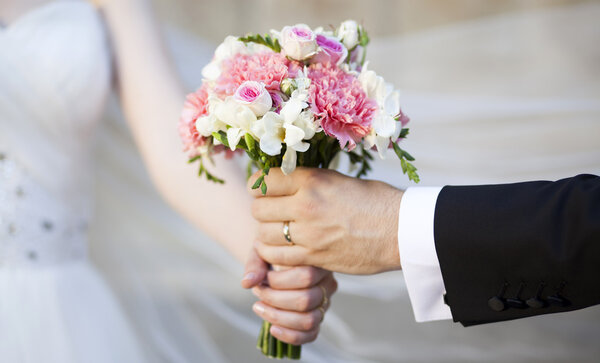 Hands and rings on wedding bouquet