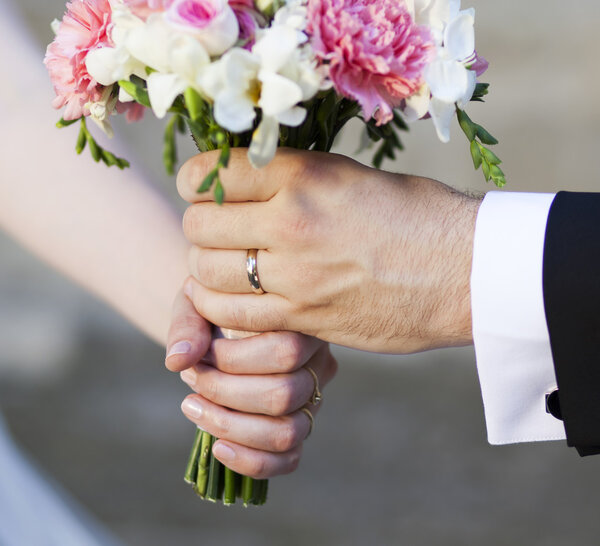 Hands and rings on wedding bouquet