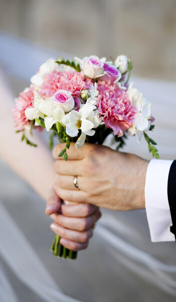 Hands and rings on wedding bouquet