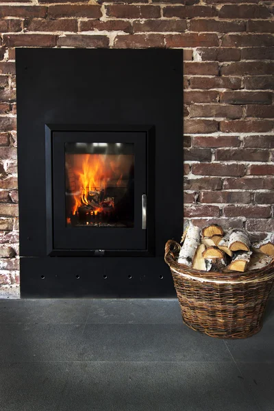 Open haard in een bakstenen muur en bossen in mand — Stockfoto