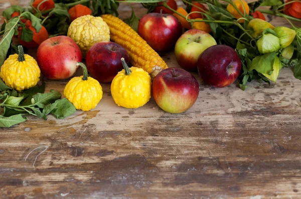 Kürbisse, Äpfel, Mais und Physalis auf Holztisch — Stockfoto