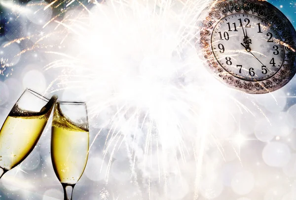 Champagne glasses, clock and fireworks at midnight — Stock Photo, Image