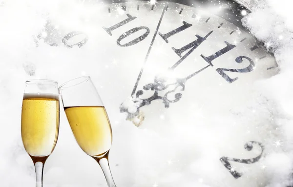 Glasses with champagne against fireworks and clock close to midnight — Stock Photo, Image