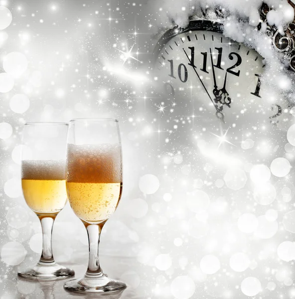 Glasses with champagne against fireworks and clock close to midnight — Stock Photo, Image