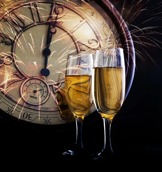 Vasos con champán contra fuegos artificiales y reloj cerca de medianoche —  Fotos de Stock