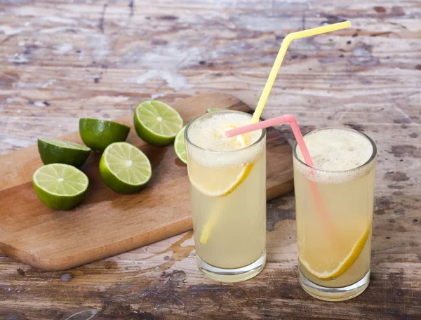 Limas frescas e limonada sobre fundo de madeira — Fotografia de Stock