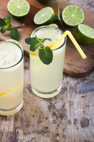 Frische Limetten und Limonade auf Holzgrund — Stockfoto