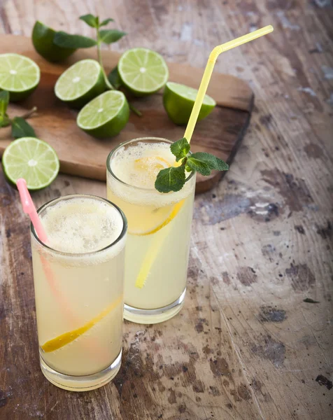 Limes fraîches et limonade sur fond bois — Photo