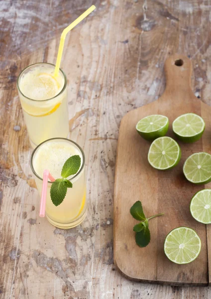 Limas frescas y limonada sobre fondo de madera — Foto de Stock