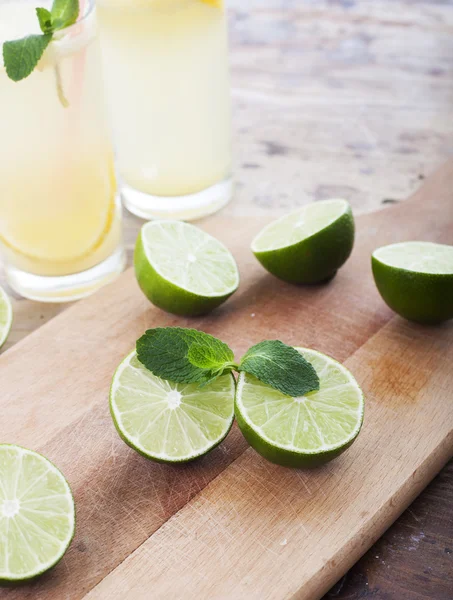 Fresh limes and lemonade on wooden background — Stock Photo, Image
