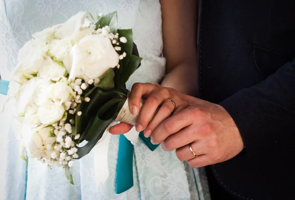 Handen en ringen op bruiloftsboeket — Stockfoto