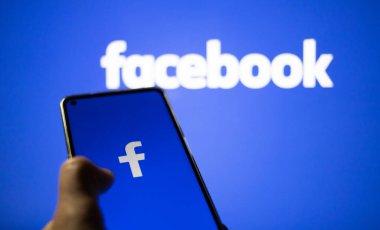 CLUJ-NAPOCA, ROMANIA - Ekim 2021: Bir kişi Facebook rrom akıllı telefonu ve bilgisayarına giriş yapıyor.