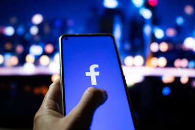 CLUJ-NAPOCA, ROMANIA - Ekim 2021: Bir kişi Facebook rrom akıllı telefonu ve bilgisayarına giriş yapıyor.