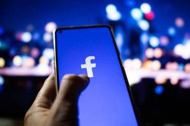 CLUJ-NAPOCA, ROMANIA - Ekim 2021: Bir kişi Facebook rrom akıllı telefonu ve bilgisayarına giriş yapıyor.