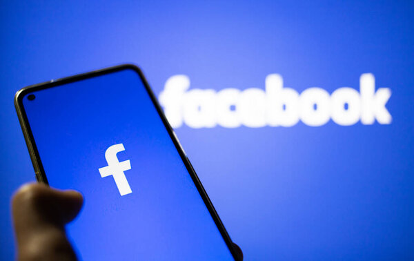 CLUJ-NAPOCA, ROMANIA - ОКТЯБРЬ 2021: Человек заходит на Facebook rrom смартфон и компьютер.