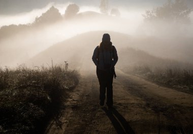 Sisli bir sonbahar manzarasında yürüyen bir adam