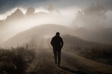 Sisli bir sonbahar manzarasında yürüyen bir adam