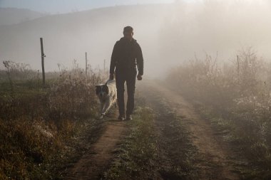 Sisli bir sonbahar manzarasında yürüyen bir adam