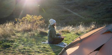 Kadın sonbaharda çadırın yanında meditasyon yapıyor.