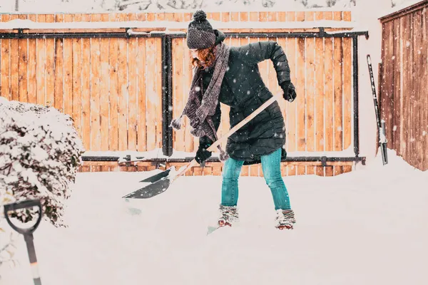 一个女人拿着铲子在车里扫雪 暴风雪过后正在除雪 — 图库照片