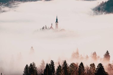 Sisli bir sabahta, Bled Blejsko Jezero Gölü 'nün muhteşem manzarası. Küçük bir adada Maria' nın Hacı Kilisesi ve arka planda Kanlı Kale ve Julian Alps.