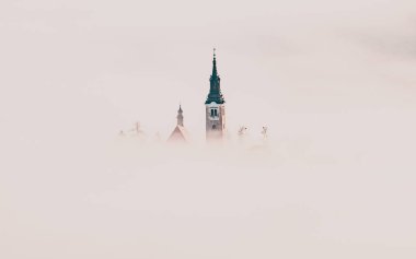 Sisli bir sabahta, Bled Blejsko Jezero Gölü 'nün muhteşem manzarası. Küçük bir adada Maria' nın Hacı Kilisesi ve arka planda Kanlı Kale ve Julian Alps.