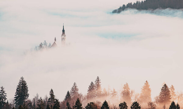 amazing panorama of Lake Bled Blejsko Jezero on a foggy morning with the Pilgrimage Church of the Assumption of Maria on a small island and Bled Castle and Julian Alps in backgroud