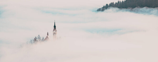 amazing panorama of Lake Bled Blejsko Jezero on a foggy morning with the Pilgrimage Church of the Assumption of Maria on a small island and Bled Castle and Julian Alps in backgroud