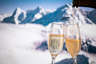 Şampanya bardakları ve arka planda karlı zirveler