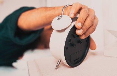 man closing alarm clock in the morning