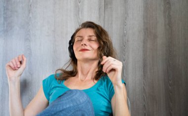Kulaklıklı, müzik dinleyen mutlu ve rahat bir kadın.