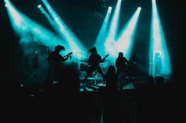 Konserdeki kalabalık ve sahne ışıklarındaki siluetler
