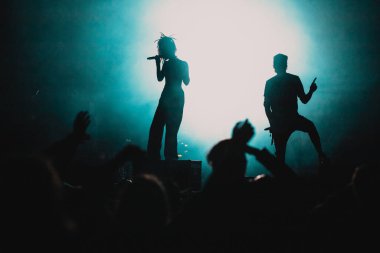 Konserdeki kalabalık ve sahne ışıklarındaki siluetler