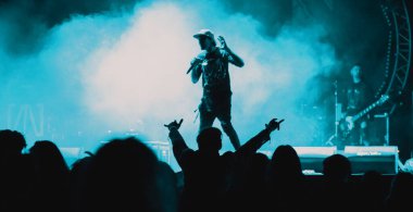 Konserdeki kalabalık ve sahne ışıklarındaki siluetler