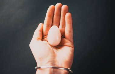 Elinde vajina yumurtası tutan bir kadın. Gül kuvars kristal yeşim yumurtası, uzayı kopyala