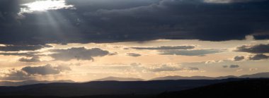 Yazın başında yeşil tepelerin üzerinde gün batımı.