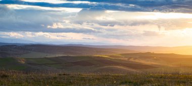 Yazın başında yeşil tepelerin üzerinde gün batımı.